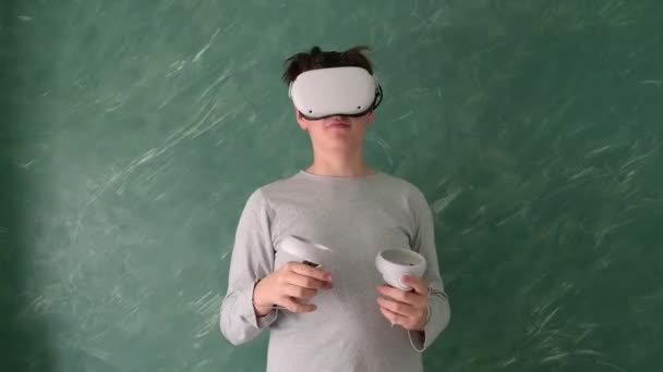 мальчик играет с виртуальной гарнитурой VR на зеленом фоне - Кадры, видео