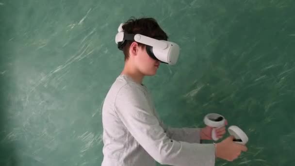 een jongen speelt met virtuele vr-headset op een groene achtergrond - Video