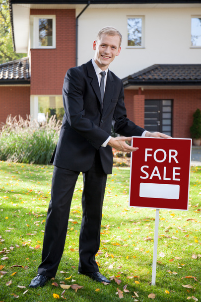Agente inmobiliario sosteniendo letrero afuera
  - Foto, imagen