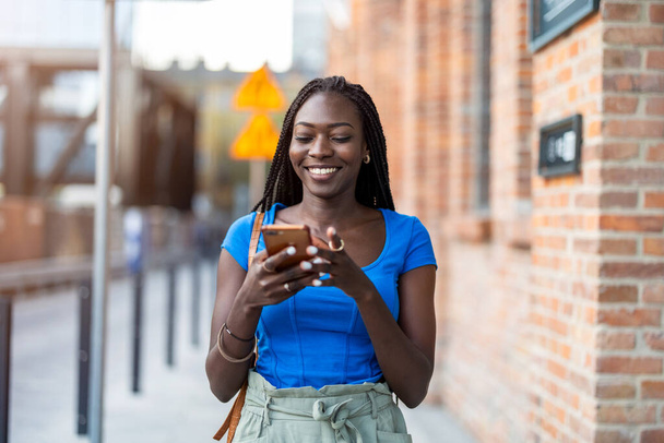 Muotokuva nuori nainen käyttää matkapuhelinta kaupungissa - Valokuva, kuva
