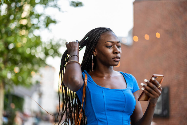 Egy fiatal nő portréja, aki mobiltelefont használ a városban. - Fotó, kép