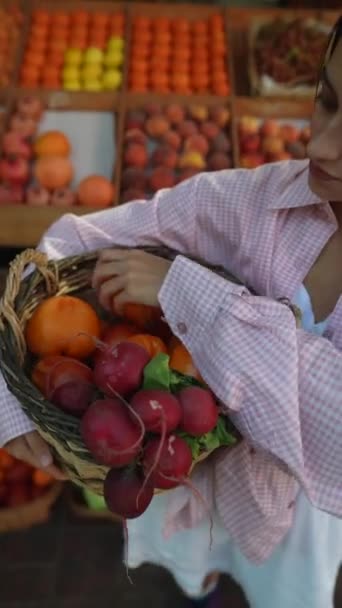 Una bella giovane venditrice con un cesto di verdure al mercato agricolo europeo. Filmati 4k di alta qualità - Filmati, video