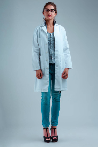 Woman in white coat and glasses, dressed stylishly with jeans, heels, striped blouse. Full-length portrait, displaying a listening and waiting expression - Photo, Image