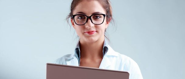 Scienziata sorridente in occhiali e cappotto, offrendo rassicurazione fattuale mentre alza lo sguardo dal suo tablet digitale, pronta a fornire consigli essenziali - Foto, immagini