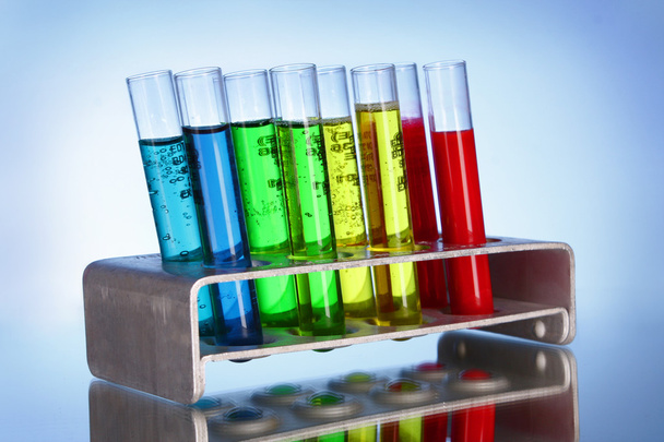 Multicoloured test tubes in the stand on blue background - Foto, Bild