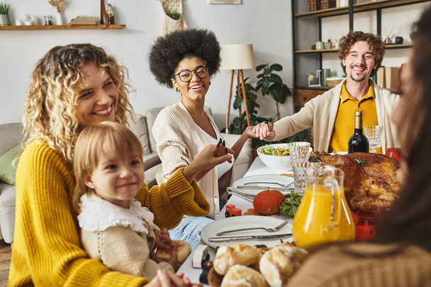 радісна багатоетнічна сім'я, що тримає руки і молиться за столом подяки, вдячна за їжу - Фото, зображення