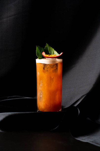 cocktail - infused tequila with basil, passion fruit and cinnamon, lime and mango in glass on dark background - Foto, afbeelding