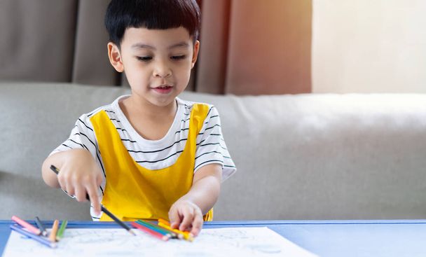 Muotokuva pieniä lapsia Aasian poika smilling kun piirustus ja väritys hänen taidekirja pöydällä olohuoneessa. Luovuuden kehittämisen käsite. - Valokuva, kuva