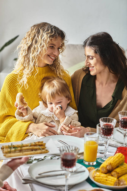 joyful lesbian couple and toddler baby enjoying delicious dinner while gathering on Thanksgiving - Fotoğraf, Görsel