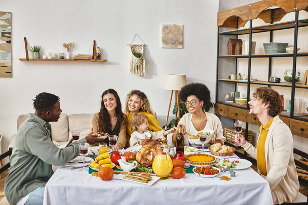 радостные многонациональные друзья и семья делятся вкусный ужин во время празднования Дня благодарения вместе - Фото, изображение
