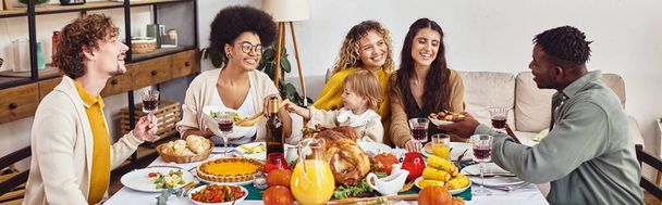 alegres amigos multiétnicos y familiares compartiendo sabrosa cena mientras celebran Acción de Gracias, pancarta - Foto, Imagen