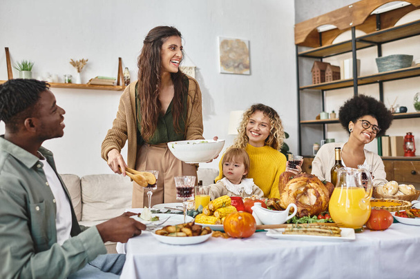 gelukkig vrouw serveren salade in de buurt multiculturele vrienden en familie tijdens Thanksgiving viering - Foto, afbeelding
