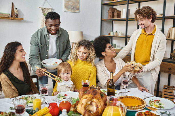 Erntedankfest, fröhliche multiethnische Freunde und Familie am Tisch mit Truthahn - Foto, Bild