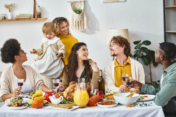 Mutlu Şükran Günleri, neşeli çok kültürlü arkadaşlar ve kızarmış hindiyle masada toplanan aile üyeleri. - Fotoğraf, Görsel
