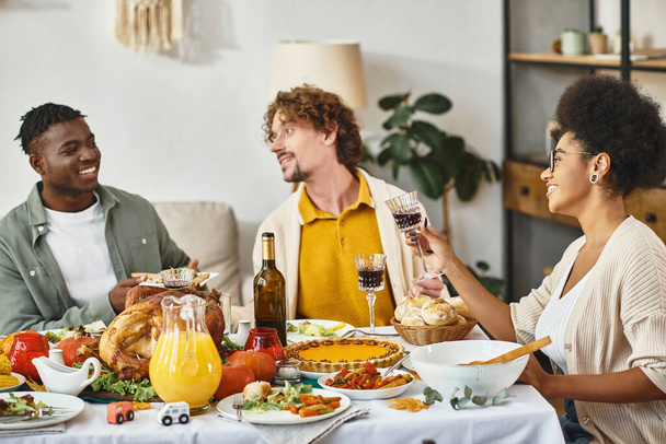 tradición de Acción de Gracias, alegres amigos multiétnicos charlando en la mesa de banquetes con pavo asado - Foto, imagen