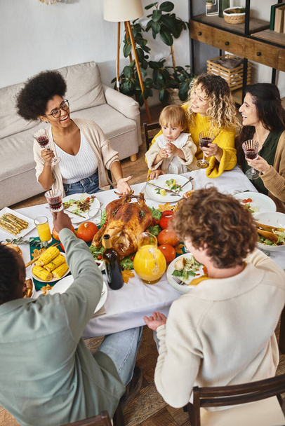 Happy multiethnic friends and family having holiday dinner while celebrating Thanksgiving - Photo, Image