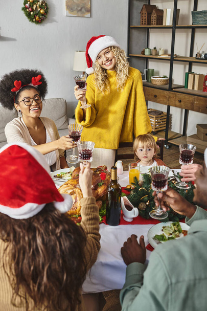 Merry Christmas celebration in warm circle of happy multicultural friends and family with baby girl - 写真・画像