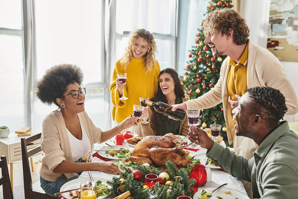 fröhliche multiethnische Verwandte, die viel Spaß miteinander haben, lachen und Wein trinken, Weihnachten - Foto, Bild