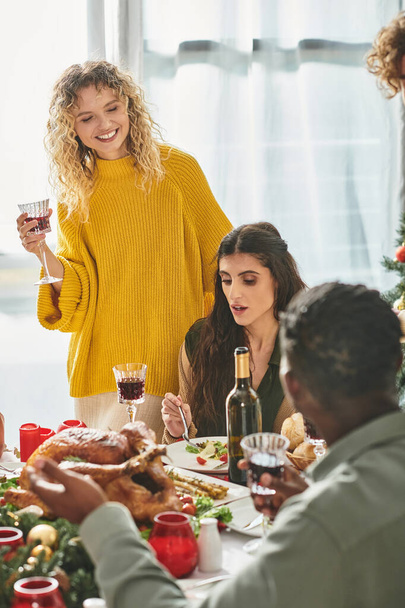 happy lgbt couple surrounded by their multiethnic relatives enjoying wine and food, Christmas - Photo, Image