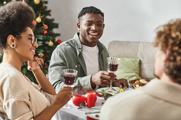 pareja afroamericana joven sentada en la mesa festiva disfrutando del almuerzo de vacaciones con la familia, Navidad - Foto, imagen