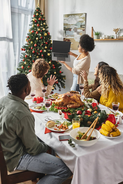 multiculturele familie met een goede tijd op feestelijke lunch en glimlachen op laptop camera, Kerstmis - Foto, afbeelding