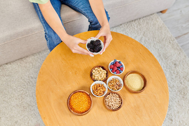 cropped view of woman with fresh blackberries near set of vegetarian products on table at home - Photo, Image