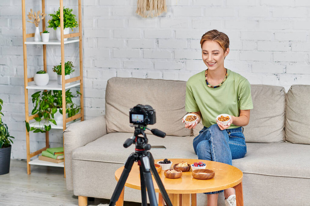 onnellinen kasvissyöjä nainen pähkinät esittää joukko kasviperäisiä ainesosia aikana video blogi kotona - Valokuva, kuva
