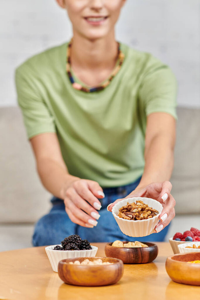 cropped view of woman with walnuts near blackberries, chickpeas and various plant-based products - Photo, Image