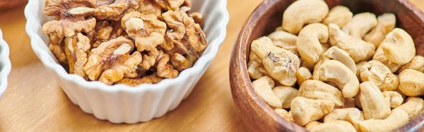 top view of high-calorie cashews and walnuts in bowls on table, plants-based diets concept, banner - Photo, Image