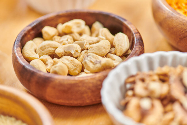 close up of delicious high-calorie cashews in wooden bowl near plant-based food, vegetarian concept - Fotó, kép