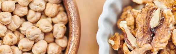top close-up zicht op calorierijke kikkererwten en walnoten in kommen, plantaardig diëten concept, banner - Foto, afbeelding