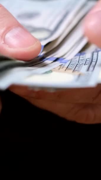 Un hombre cuenta billetes de 100 dólares. Un hombre de negocios cuenta rápidamente su fajo de efectivo. De cerca. Vídeo vertical - Metraje, vídeo