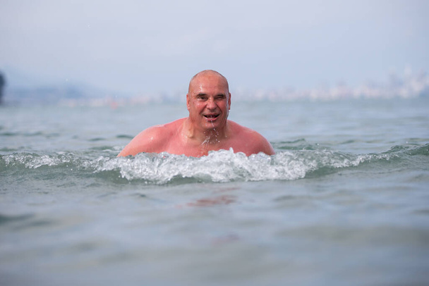 Ένας ηλικιωμένος άντρας λούζεται σε θαλασσινό νερό.. - Φωτογραφία, εικόνα