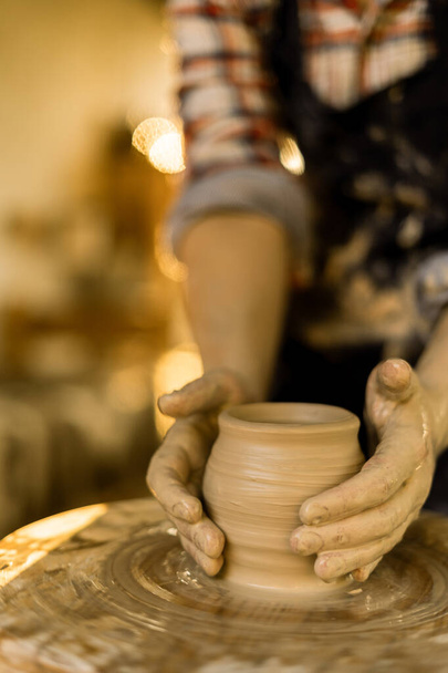 Mãos de oleiro mulher faz panela de barro ou xícara na roda de cerâmica no fundo do pôr do sol. Espaço de cópia - Foto, Imagem