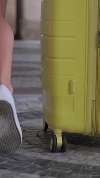 Közelkép egy női utazóról, aki poggyászban sétál az úton. Függőleges videó. - Felvétel, videó