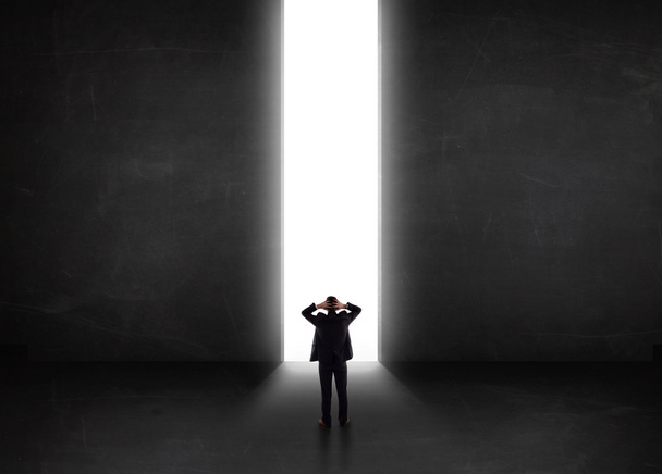 Business person looking at wall with light tunnel opening  - Photo, Image