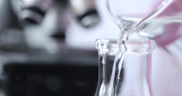 Wissenschaftler Chemiker Gießen Wasser aus dem Reagenzglas in Kolben im Labor Nahaufnahme 4k Film Zeitlupe. Konzept zur Qualitätskontrolle des Leitungswassers - Filmmaterial, Video