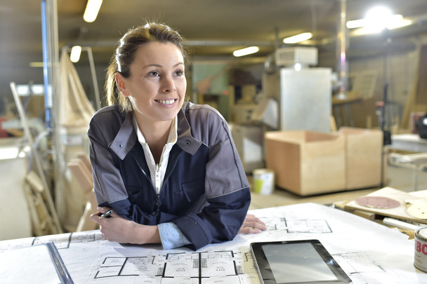 Female architect working with blueprint - Фото, изображение