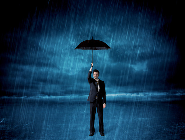 Business man standing in rain with an umbrella - Foto, afbeelding