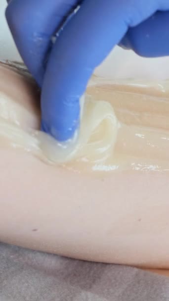 Delicate bright depilation in a cosmetology office. Waxing master. Close up. Vertical video - Footage, Video