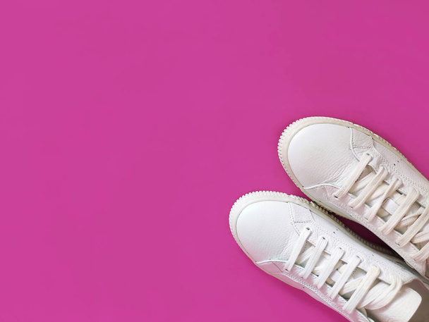 Zapatillas deportivas de piel blanca con cordones sobre fondo rosa - Foto, imagen