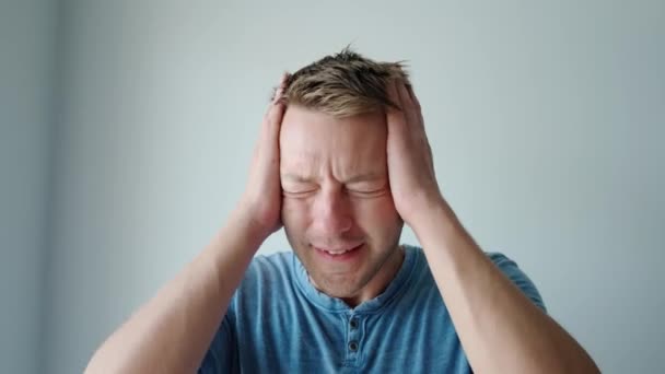 Schöner kaukasischer Mann mit Hand auf Kopf, der unter Kopfschmerzen aufgrund von Stress und Schmerzen leidet. Männchen mit Migräne. Schlechtes Gefühl - Filmmaterial, Video