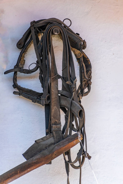 Arnés de caballo histórico colgado en la pared, como una demostración de la antigua artesanía y la vida del pueblo - Foto, Imagen