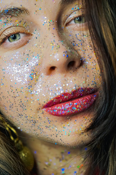 Portrait of a beautiful woman with blue sparkles on her face. Girl with colorful artistic make-up with glitter. Fashion model with colorful makeup. Festive make-up design. New Year, Christmas, birthday - Photo, Image