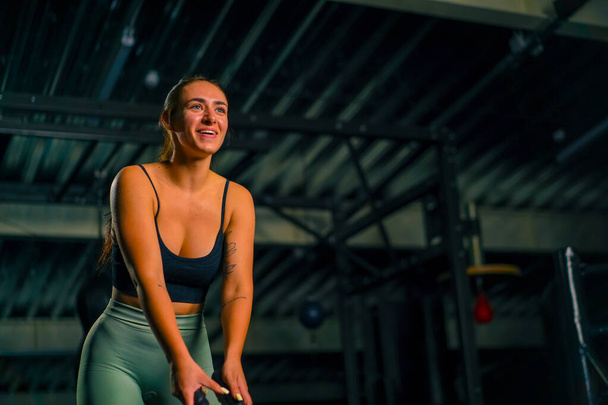 belle jeune femme de fitness faire des exercices avec une corde dans ses mains dans la salle de gym se préparant à la motivation de la compétition de musculation - Photo, image