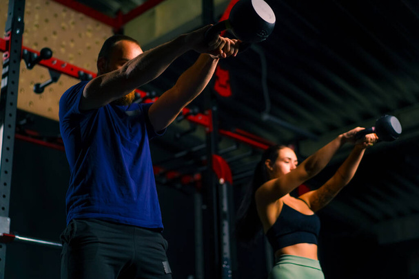 Юные спортсмены проводят групповые тренировки в спортзале делают упражнения с гирями, готовясь к соревнованиям - Фото, изображение