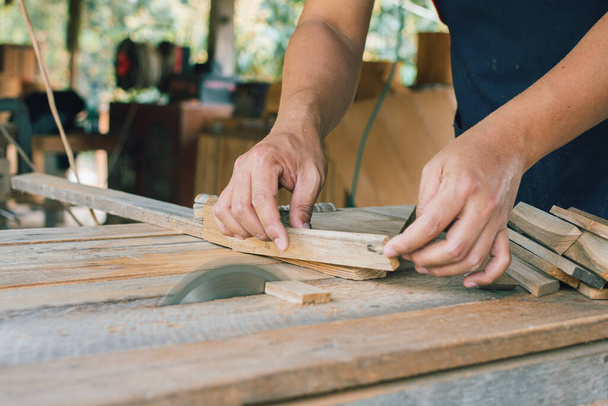 Falegname asiatico sta usando una sega circolare per tagliare il legno per costruire una scatola di stoccaggio su un tavolo da scrivania presso la sua fabbrica. Lavorare come il proprio capo a casa concetto - Foto, immagini