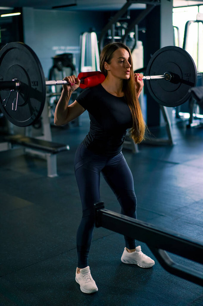 portret skoncentrowanej kobiety fitness wykonującej ciężkie ćwiczenia prasy barkowej ze sztangą w siłowni treningowe grupy mięśni - Zdjęcie, obraz