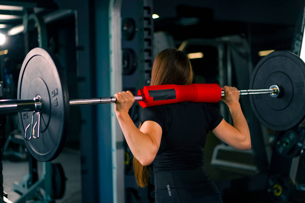 soustředěný fitness žena dělá těžké rameno stiskněte cvičení s činka tělocvična trénink svalové skupiny zpět pohled - Fotografie, Obrázek