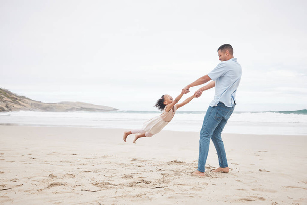 Houpání, šťastný a otec a dítě na pláži pro zábavu, sbližování a lásku v létě na dovolenou. Hravý, smějící se a mladý táta točí dívkou v oceánu za svobodou a láskou. - Fotografie, Obrázek